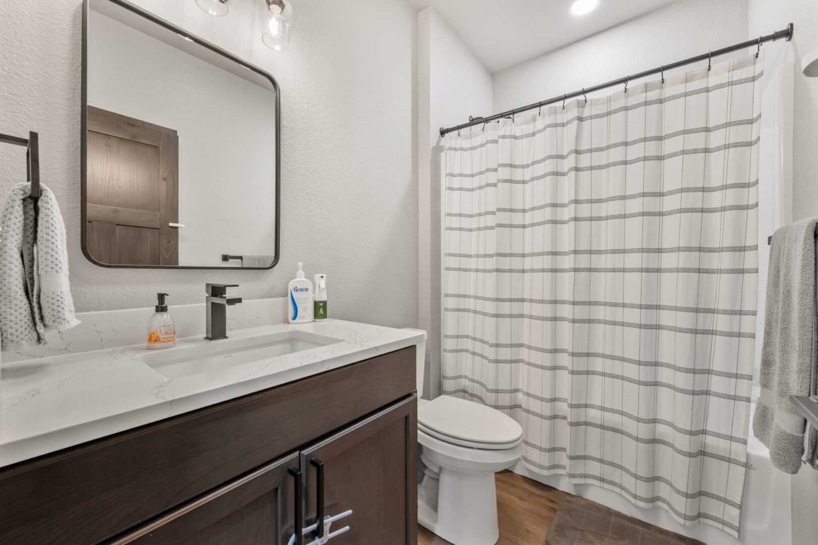 Modern bathroom with dark wood vanity and patterned shower curtain.