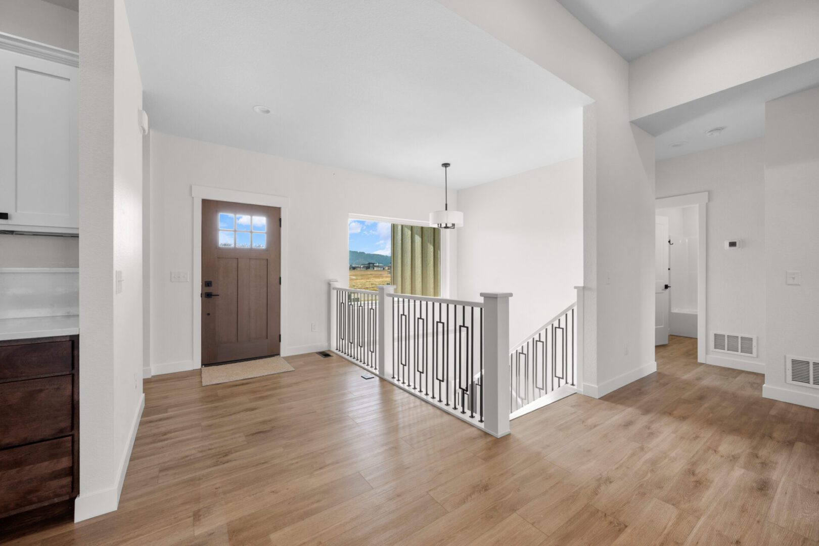 Bright entryway with wooden floors and a staircase railing.
