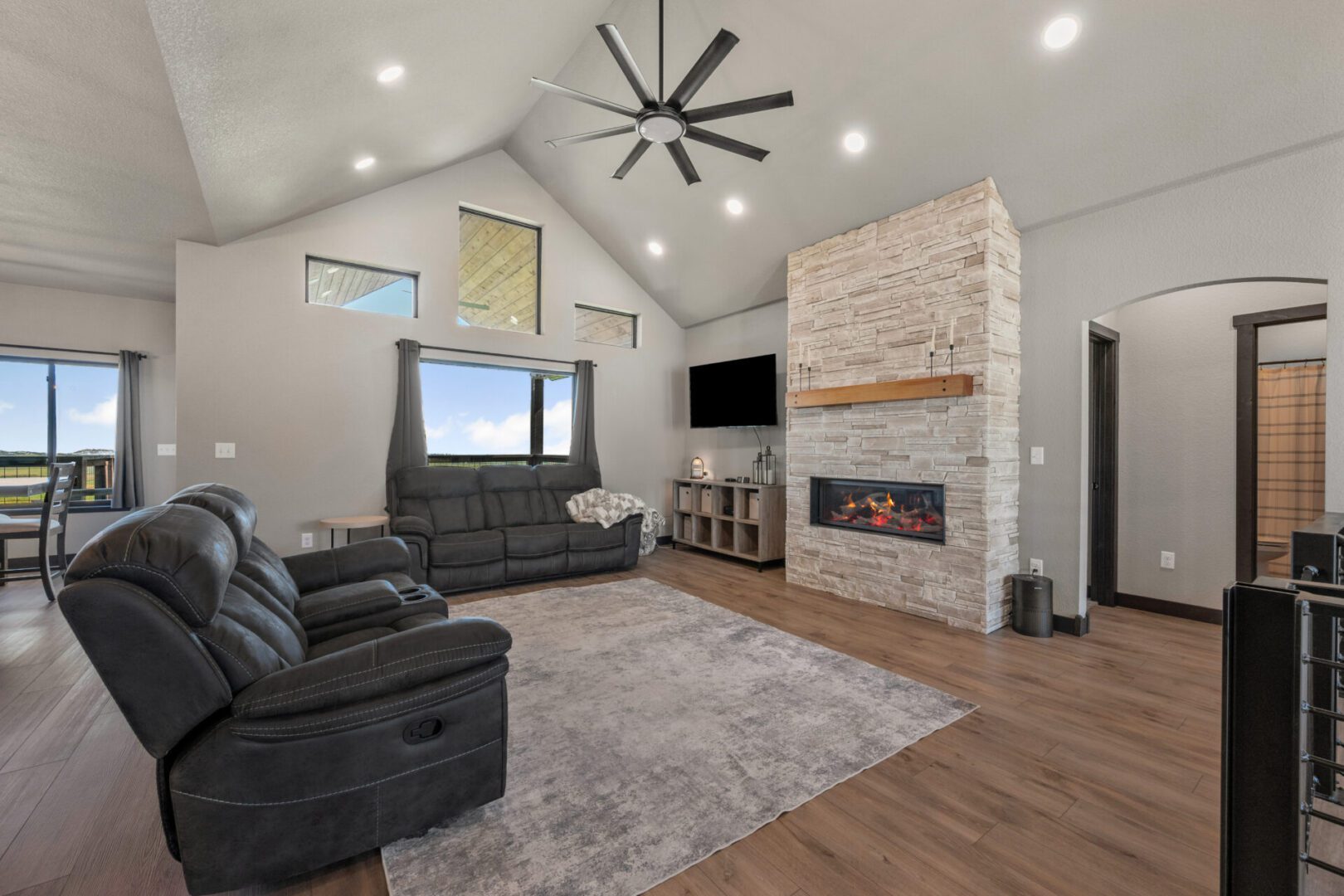 Modern living room with stone fireplace and large windows.