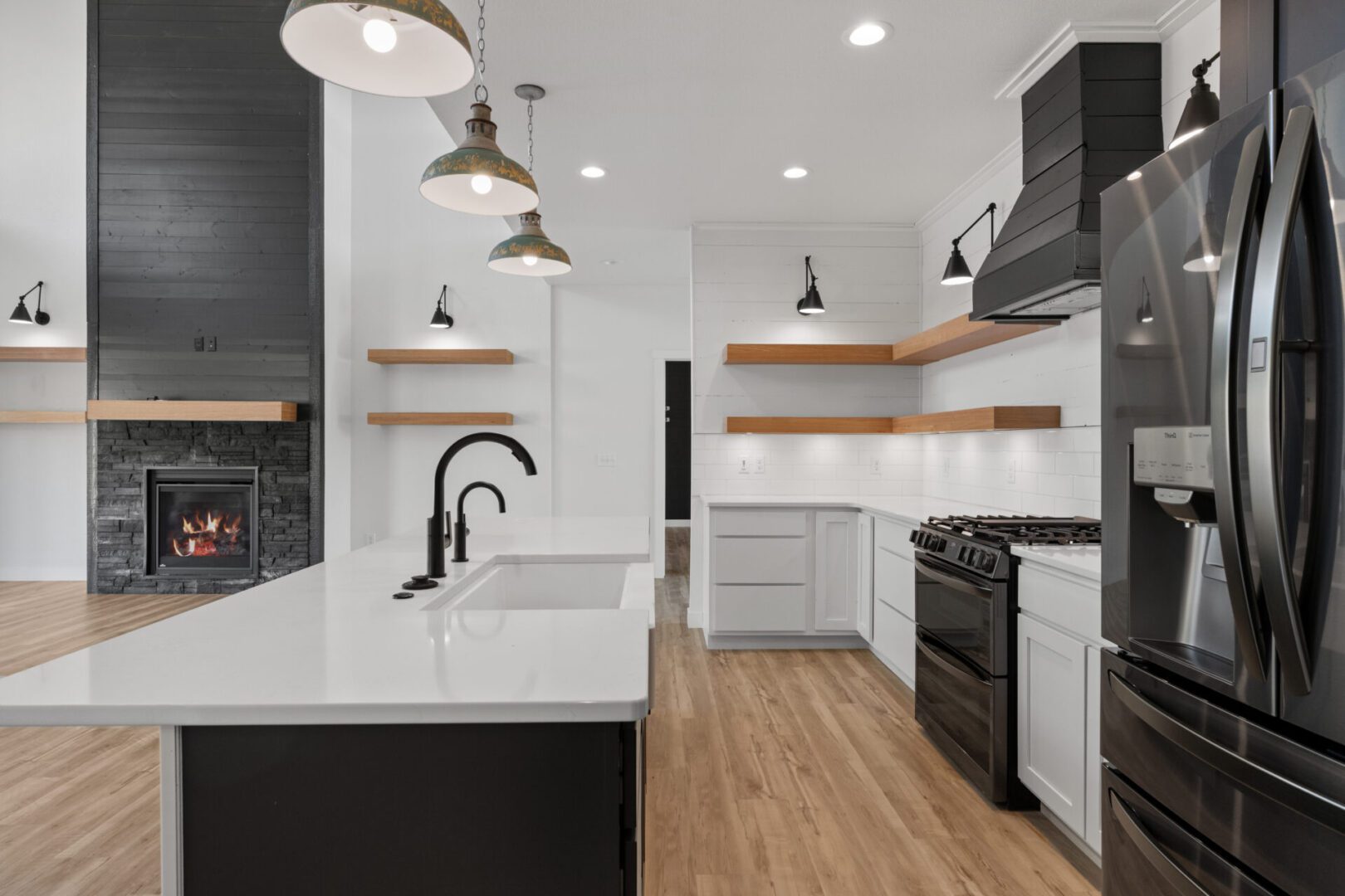 Modern kitchen with white cabinets, black fixtures, and wooden floors.