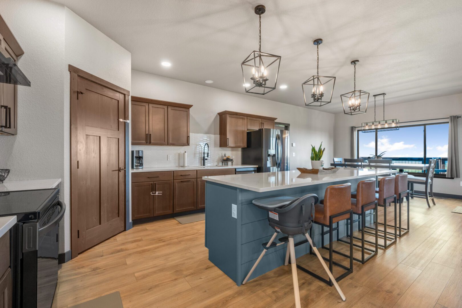 Modern kitchen with wooden cabinetry and a blue island with bar stools.