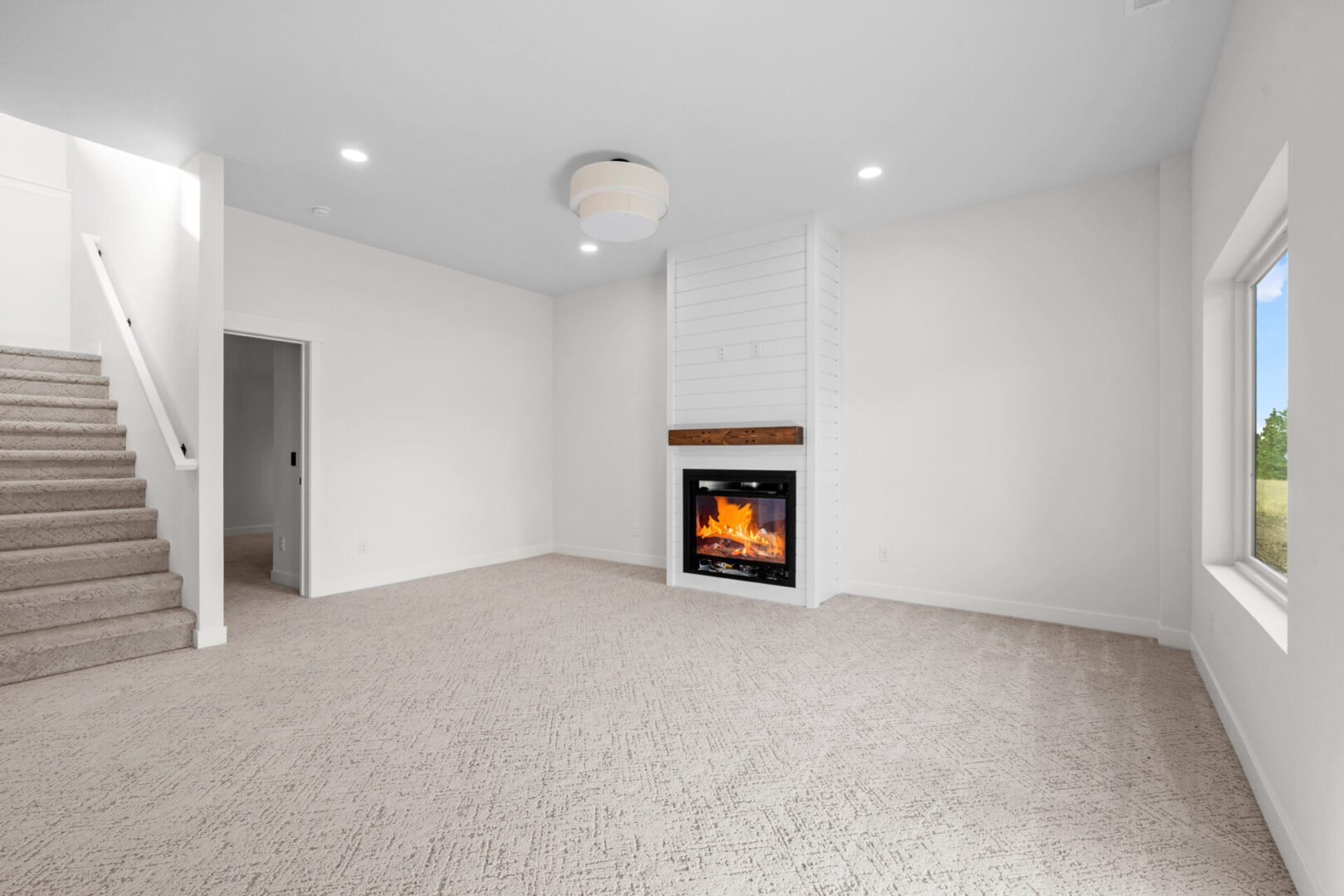 Cozy carpeted room with a modern fireplace and neutral walls.