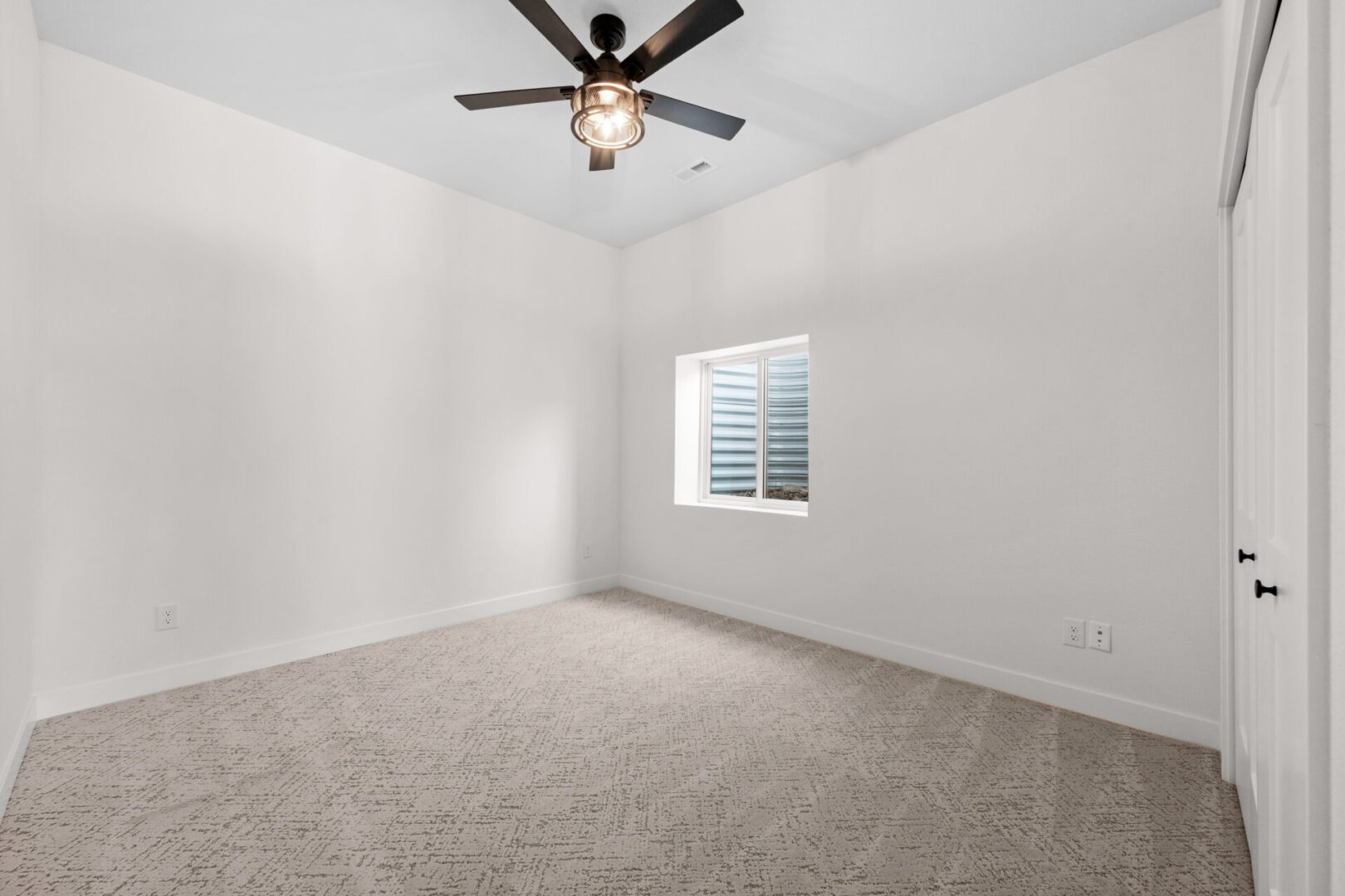 Empty room with carpet, ceiling fan, and window with blinds.