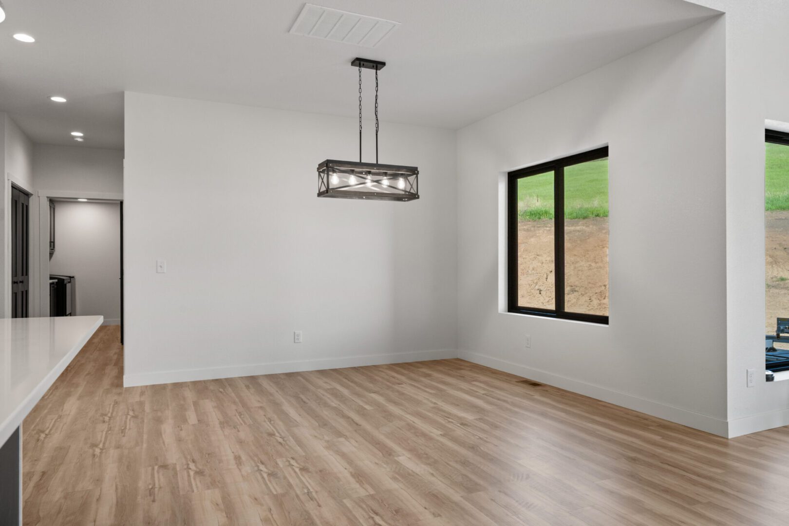 Empty modern room with wooden floor and a rectangular chandelier.