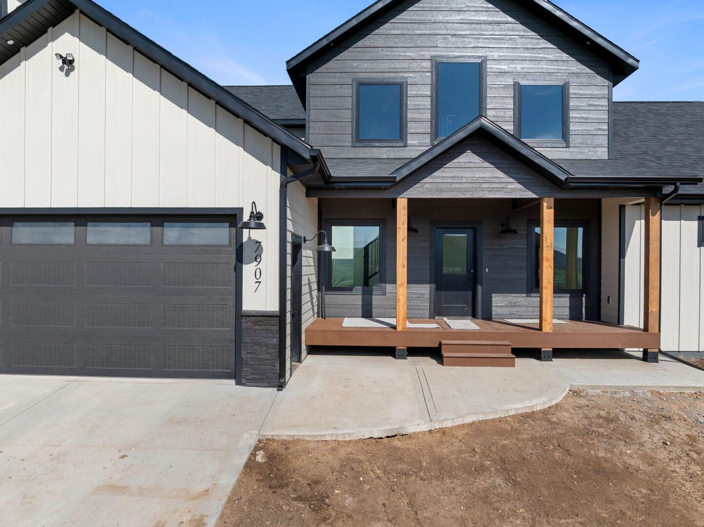 Modern two-story house with a dark exterior and a wooden porch.
