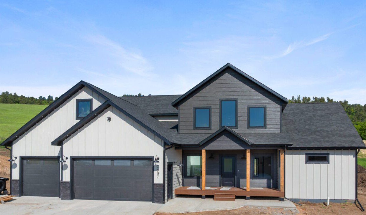 Modern two-story house with a spacious driveway and dark roof.