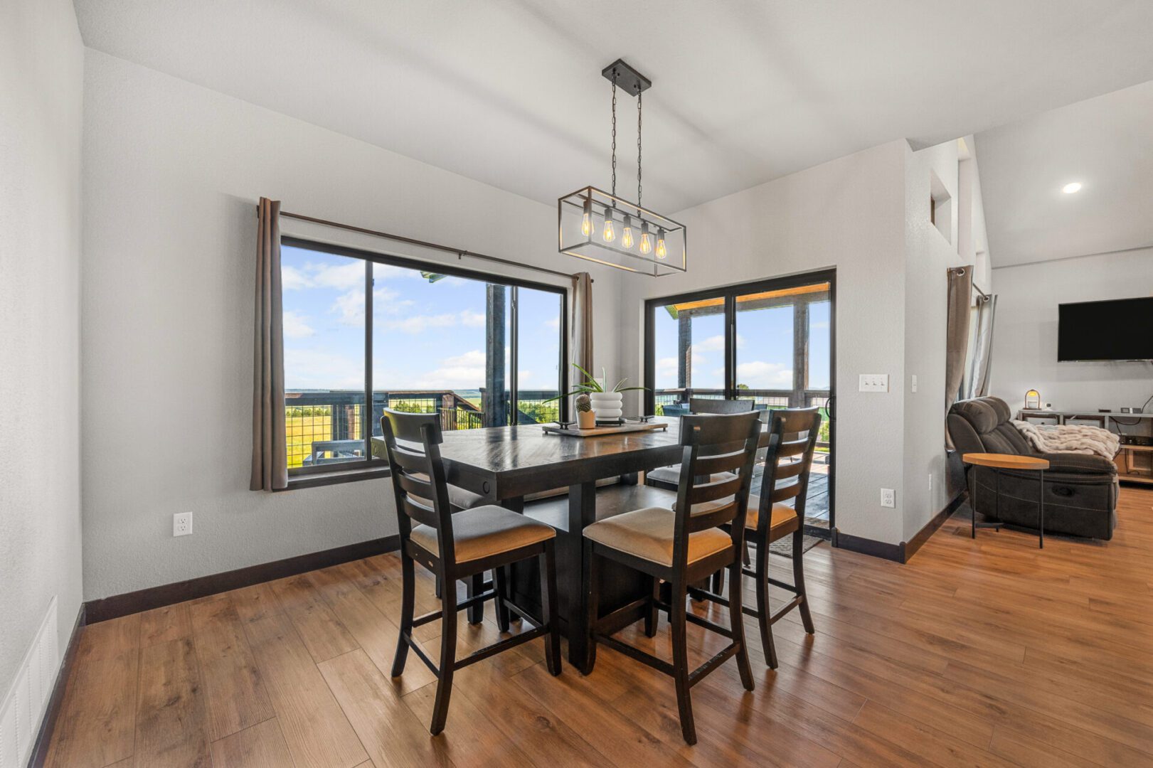 Modern dining area with wooden table and large windows offering a scenic view.
