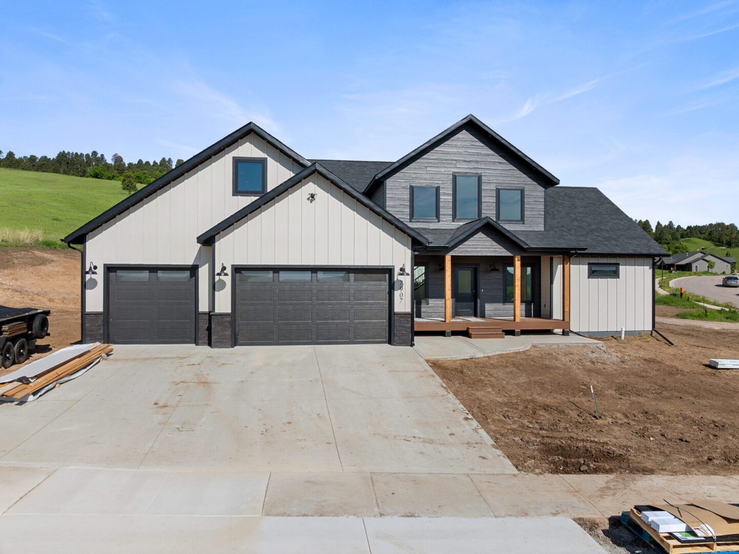 Newly built modern house with a large driveway and triple garage.