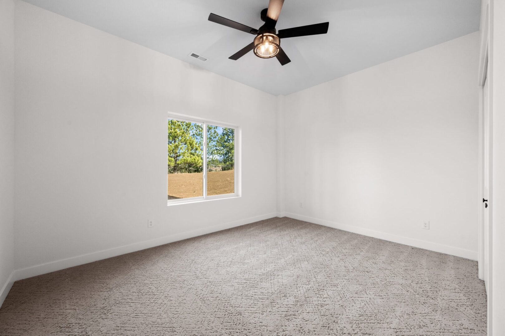 Empty carpeted room with white walls and ceiling fan.