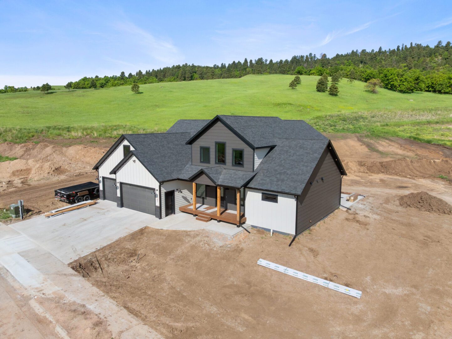 Newly constructed modern house on a cleared plot with green hills in the background.