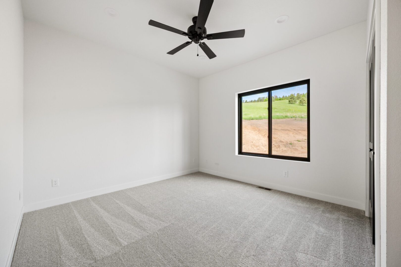 Empty room with gray carpet and ceiling fan.