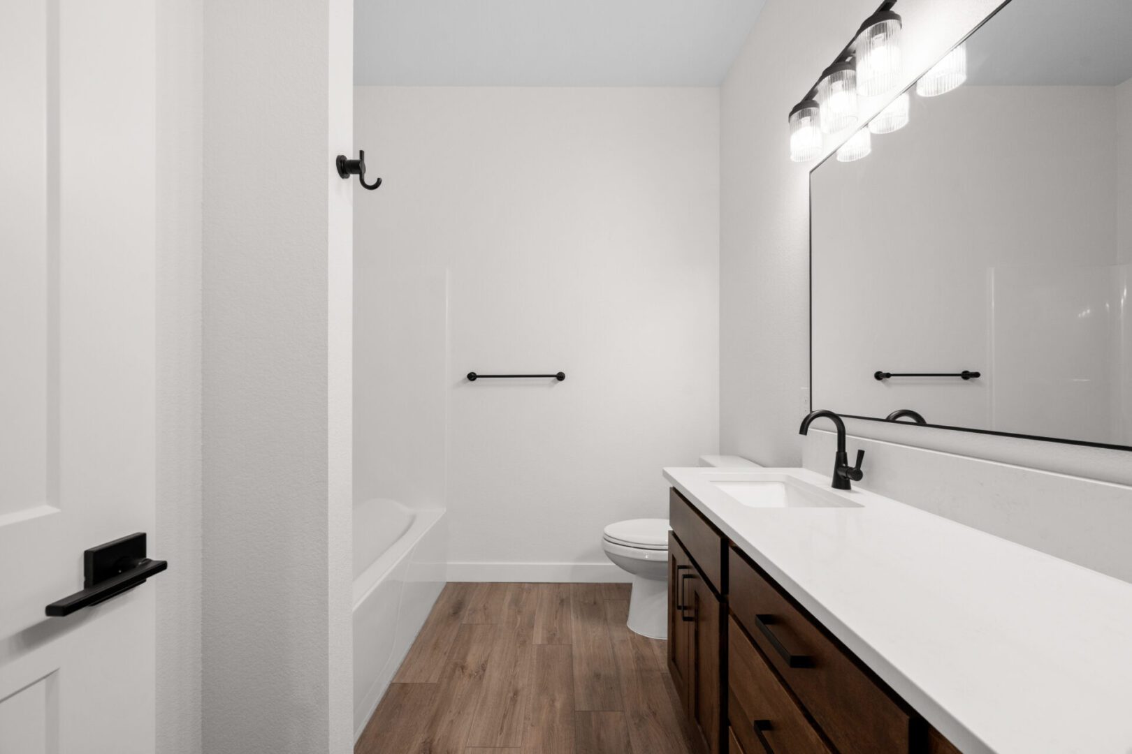 Minimalist bathroom with white walls and wooden floor.