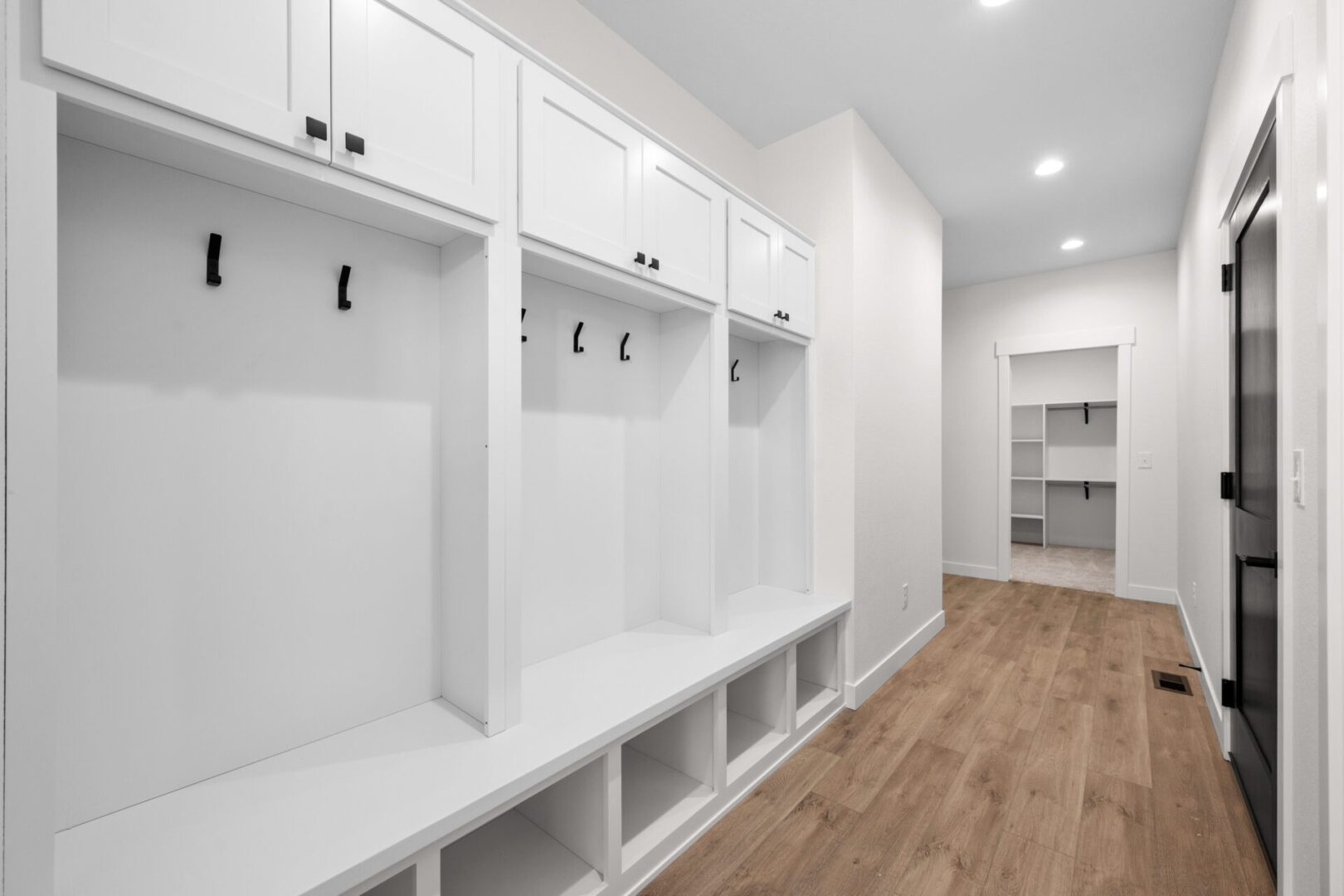 A modern, white mudroom with cubbies and hooks for storage.