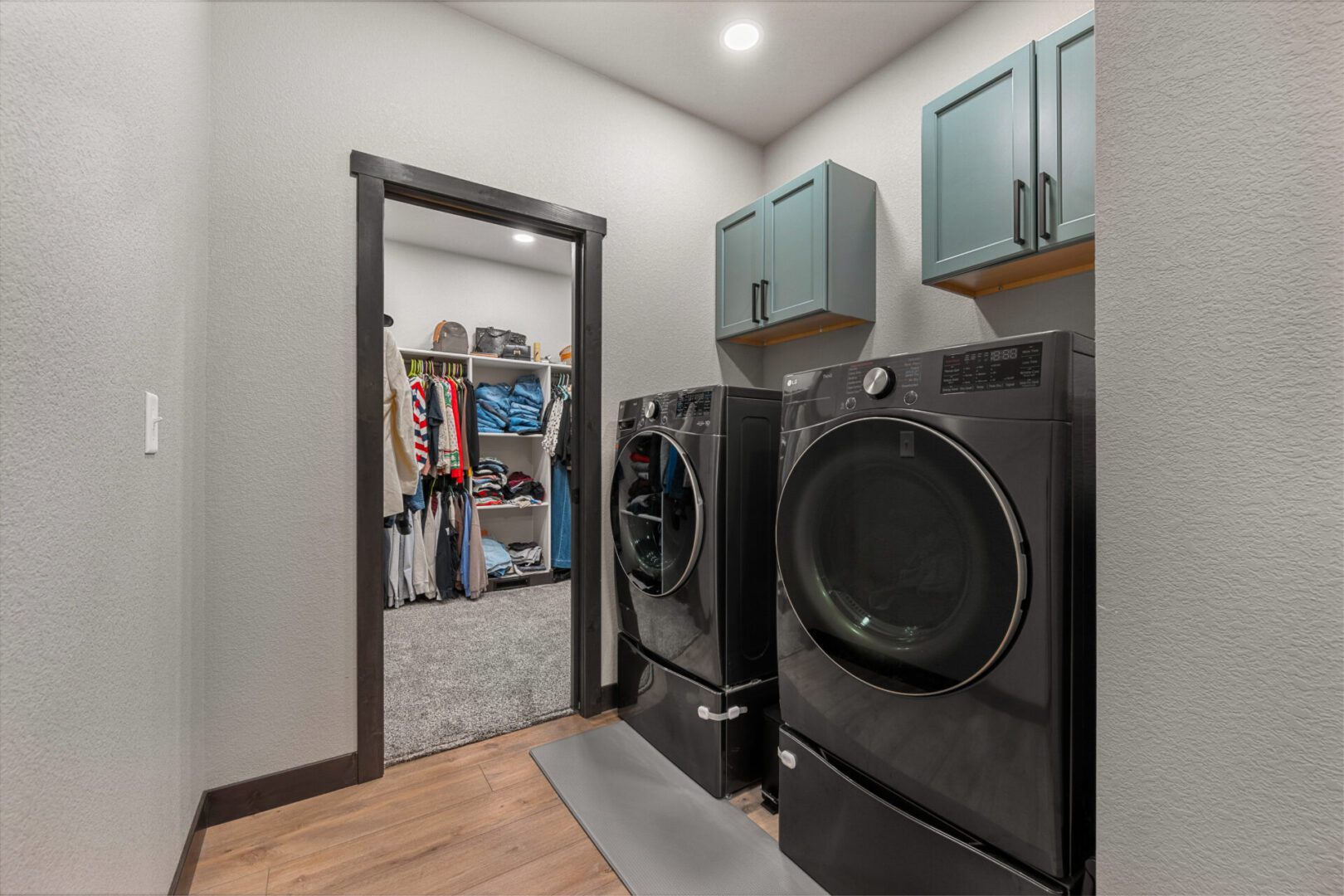 Modern laundry room with black washer and dryer, adjacent to a walk-in closet.
