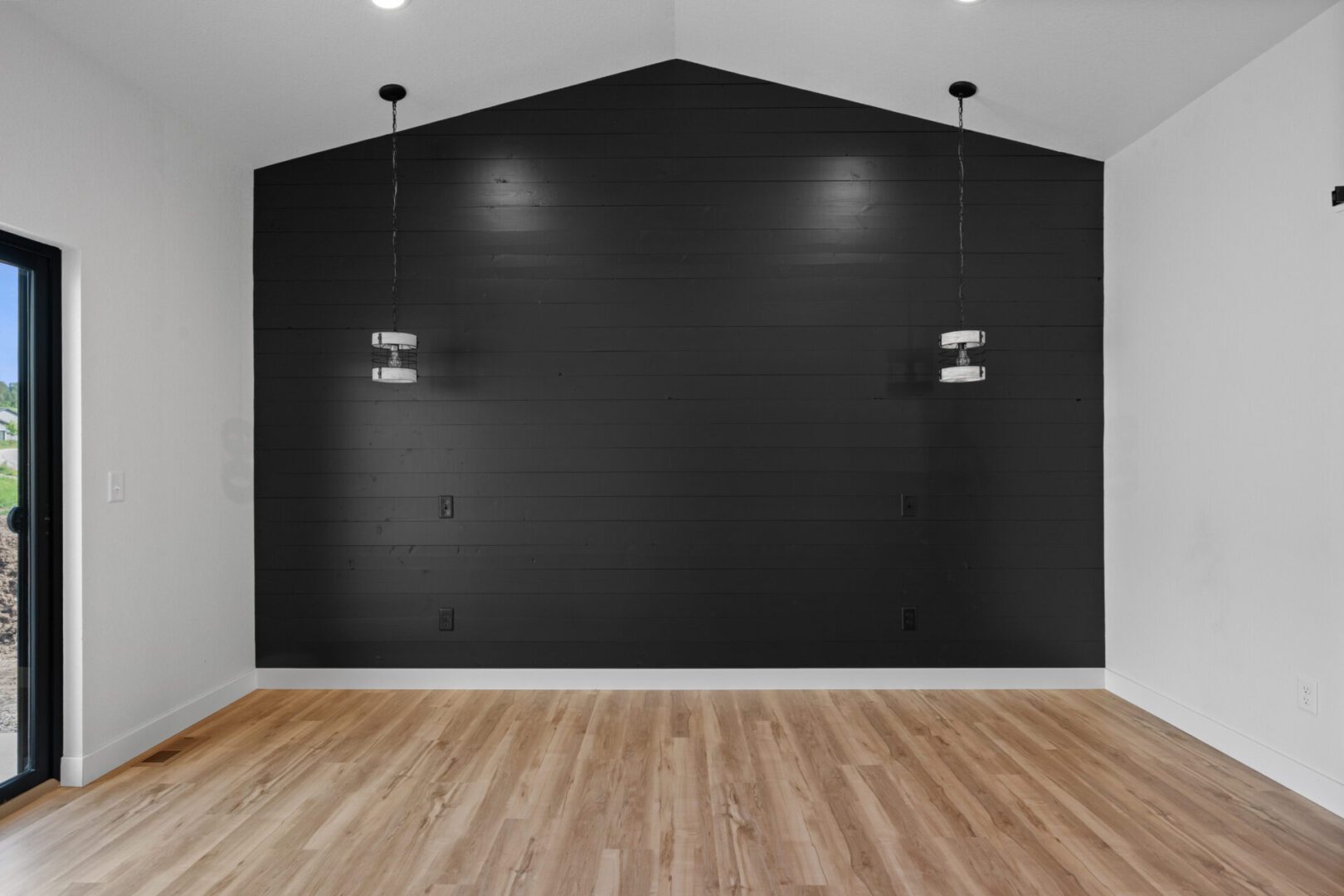 Empty room with black accent wall and wooden floor.