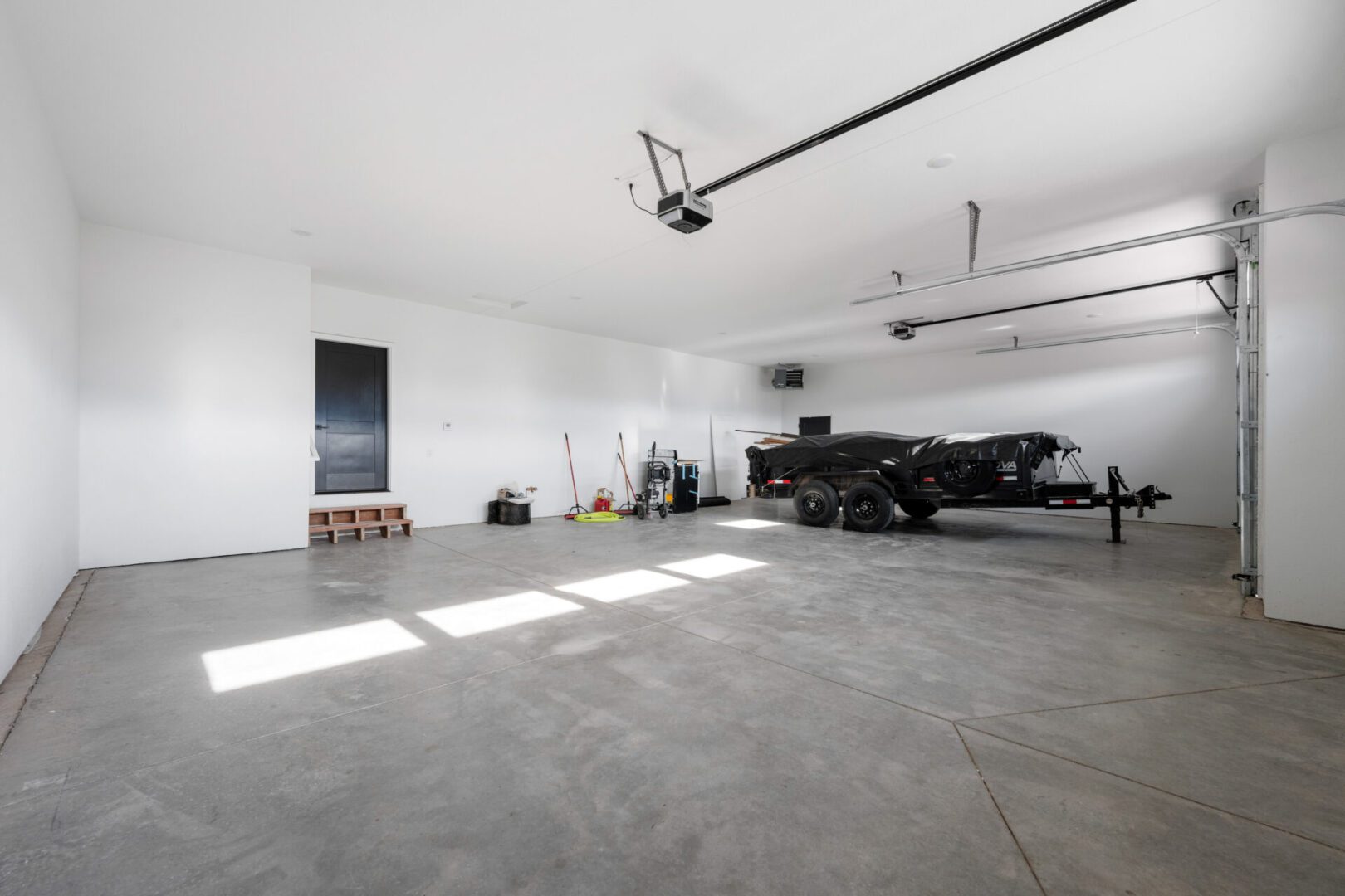 Spacious, clean garage with two cars and organized tools.