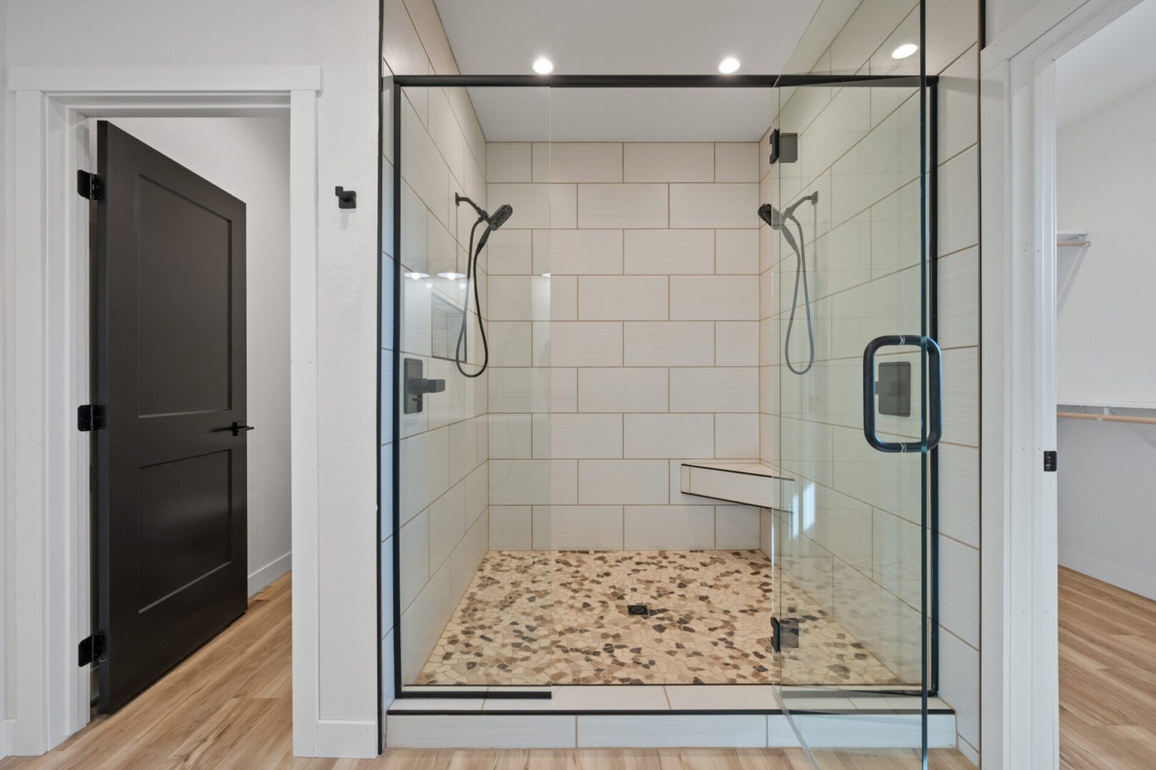 Modern walk-in shower with glass doors and stone pebble floor.