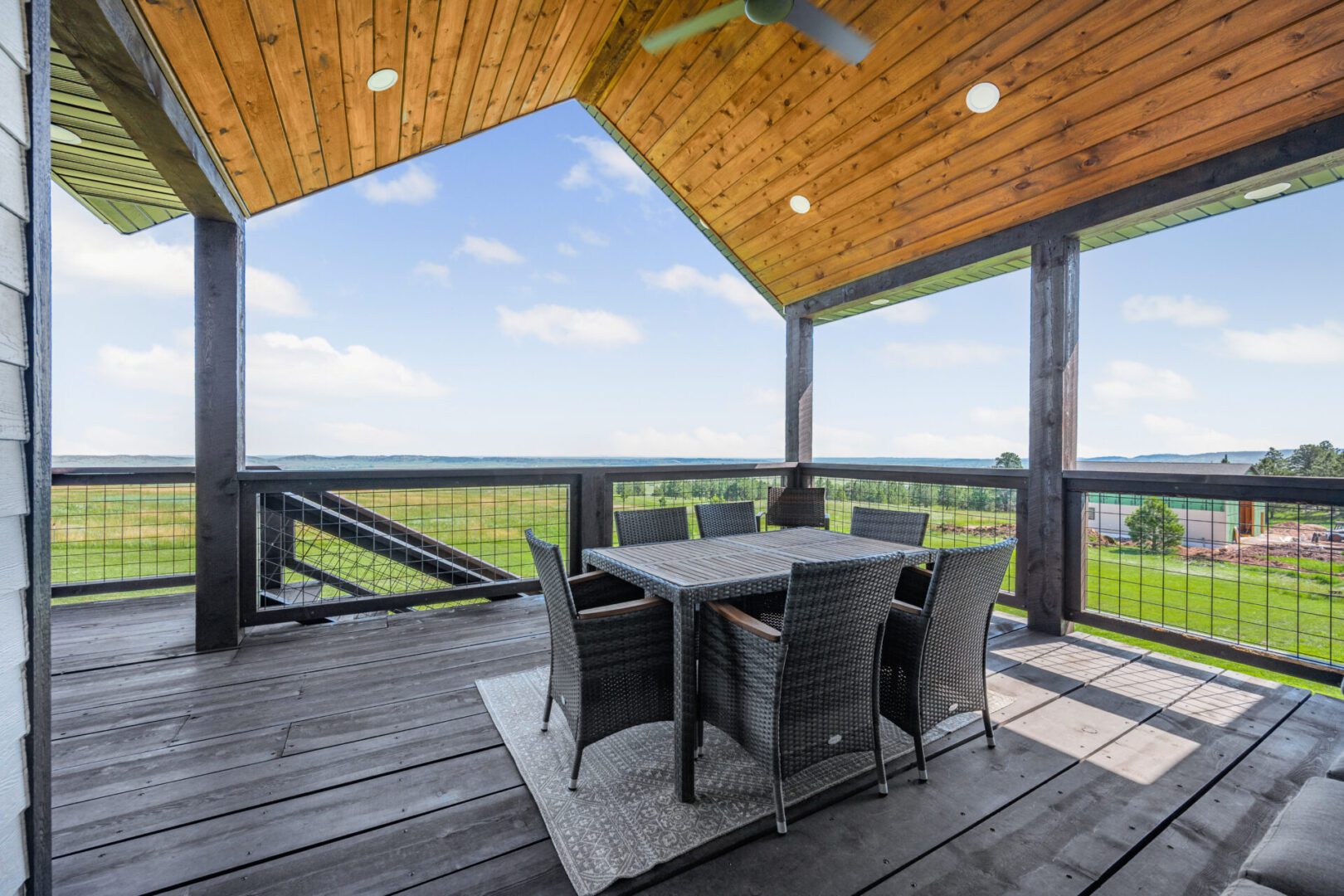 Outdoor dining area on a wooden balcony with scenic views.