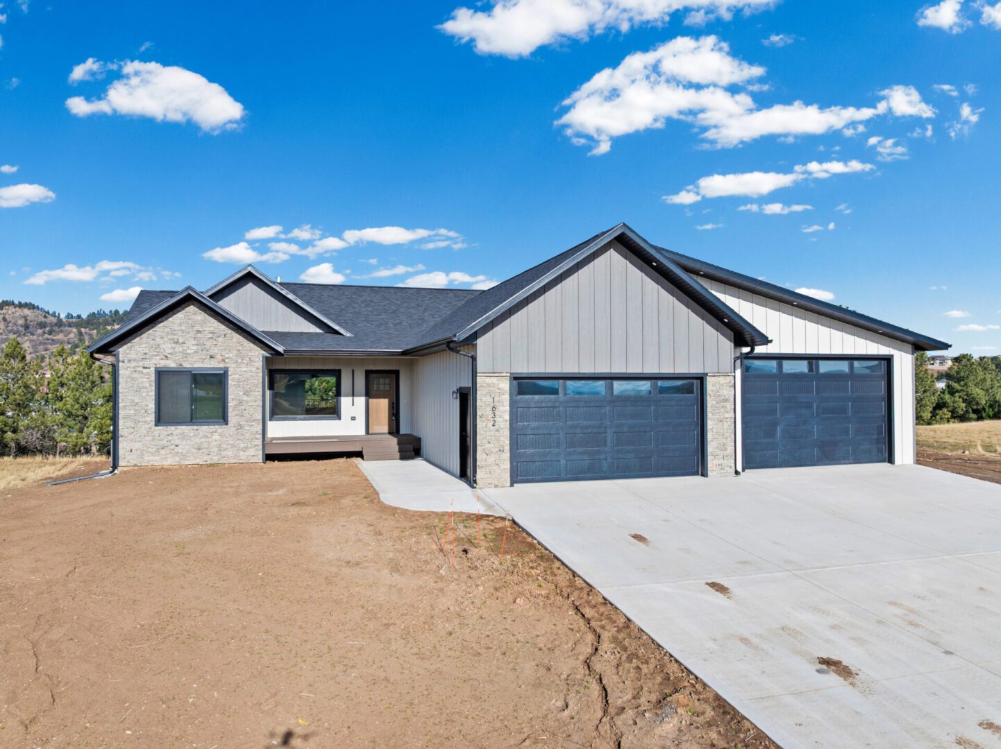 Modern single-story house with a three-car garage and a spacious driveway.