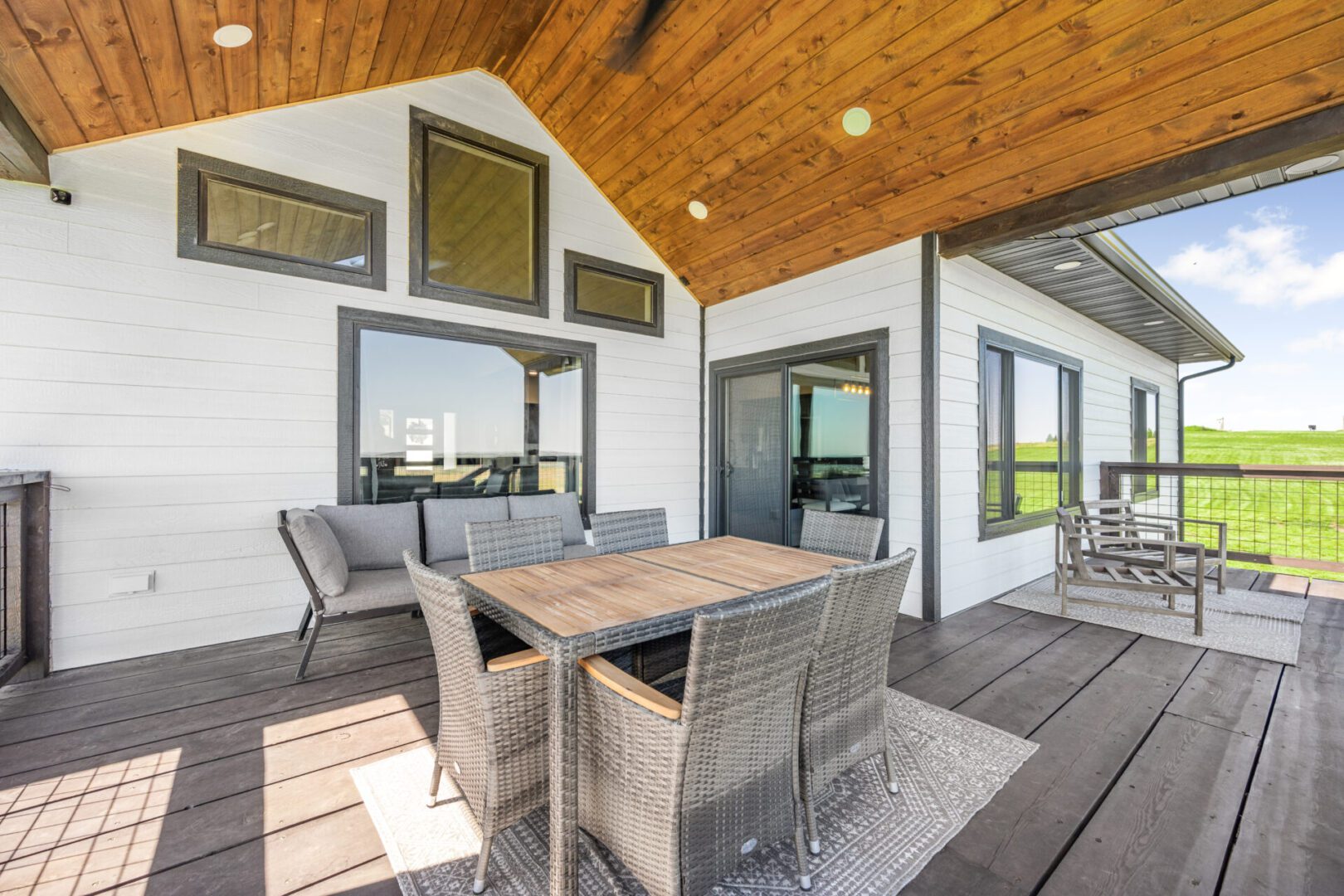 Spacious outdoor patio with modern wicker furniture and wooden ceiling.