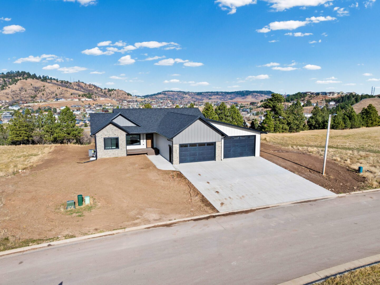 Modern single-story house with a three-car garage and spacious driveway.