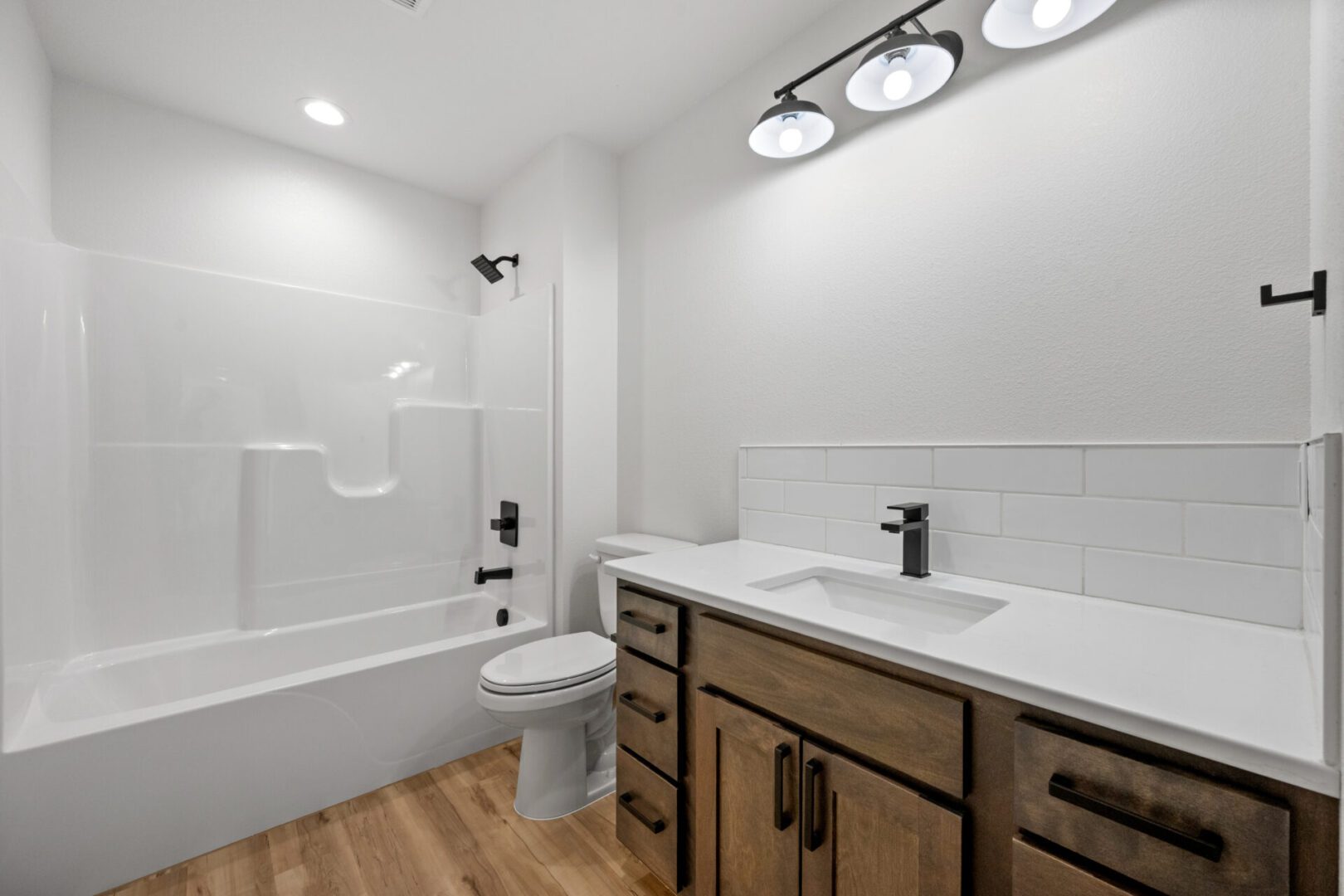 Modern bathroom with white walls, wood floor, and vanity.