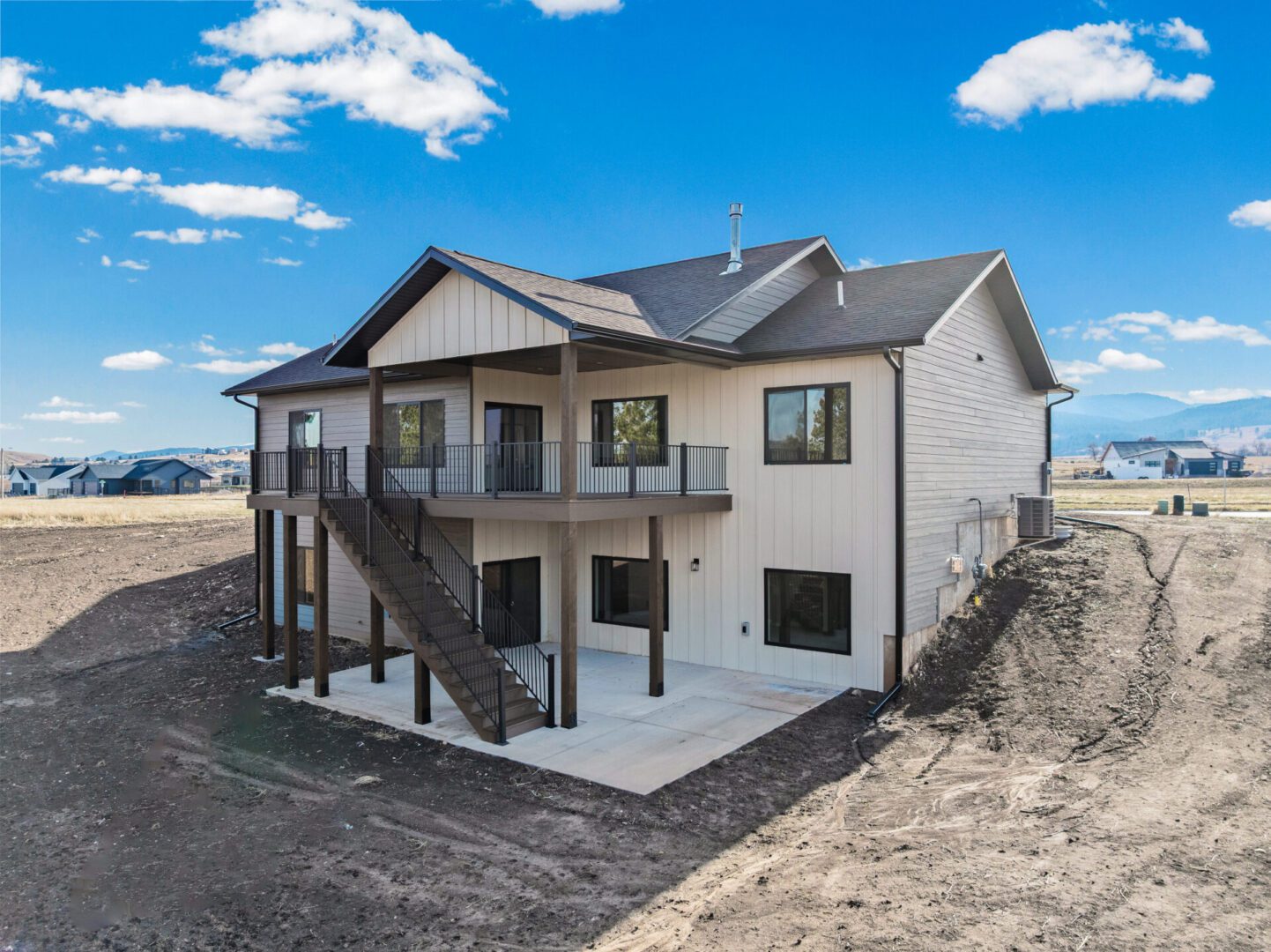 Modern two-story house with balconies and staircases in a spacious yard.