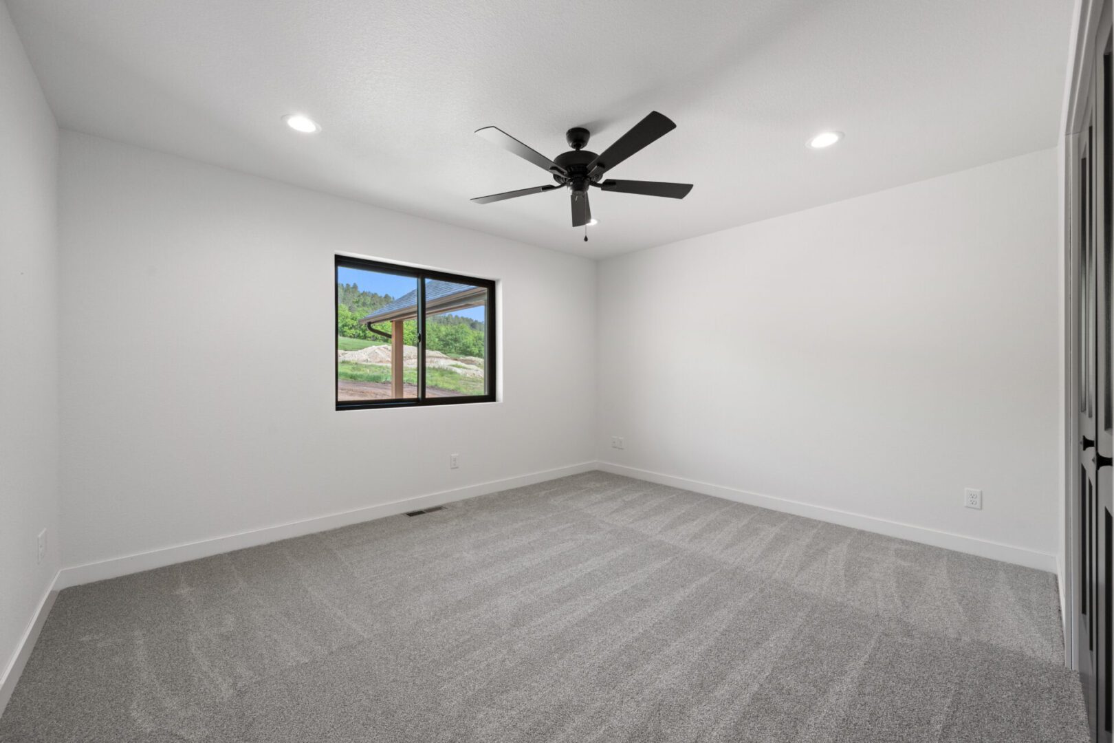 Empty room with gray carpet, white walls, and a ceiling fan.