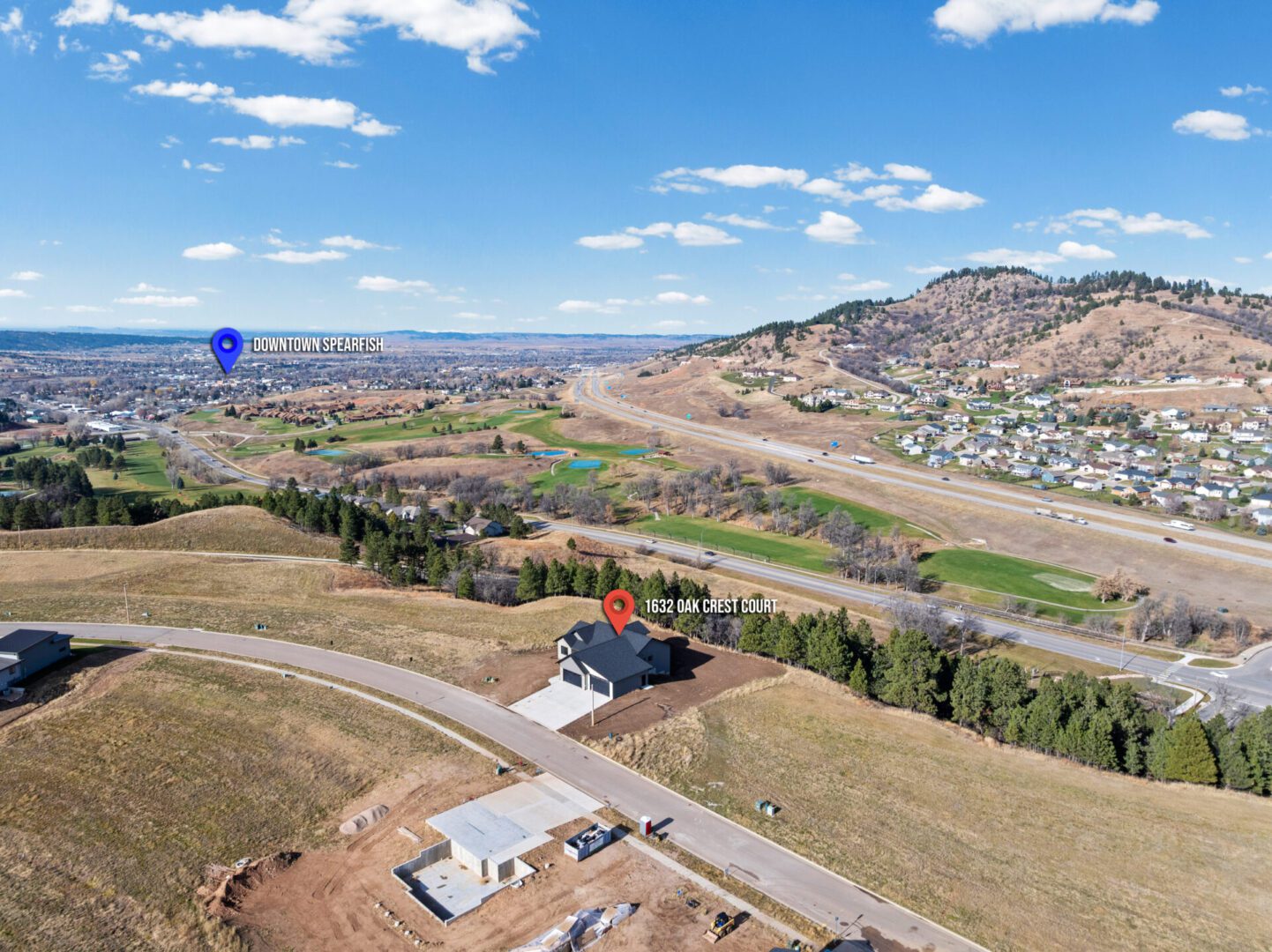 A scenic aerial view of a mountainous town under a blue sky with scattered clouds.