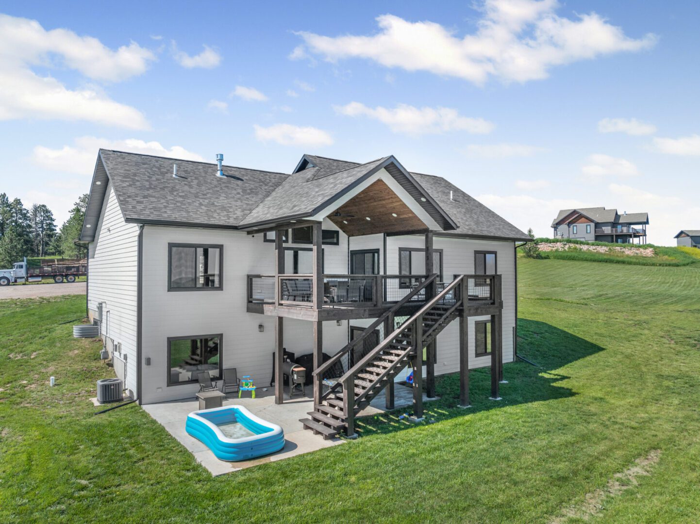 Modern two-story house with a green lawn and a small pool in the backyard.