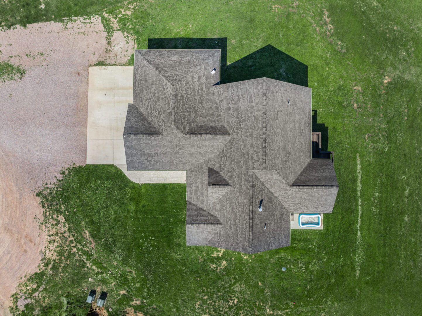 Aerial view of a large house with a complex roof and backyard pool.