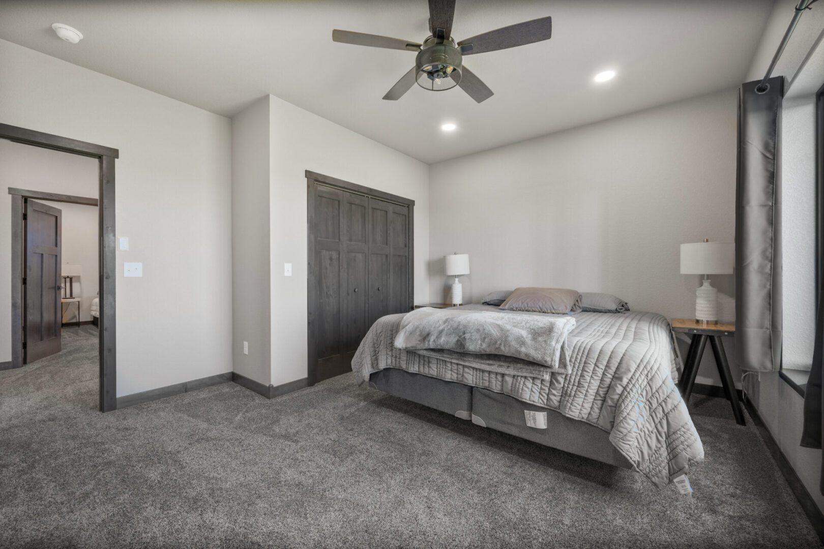 Modern bedroom with gray tones and ceiling fan.