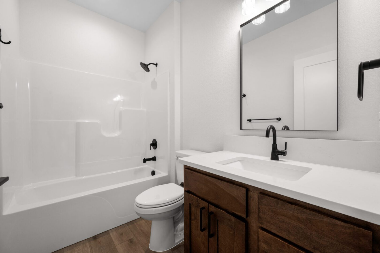 Modern bathroom with dark wood vanity and black fixtures.