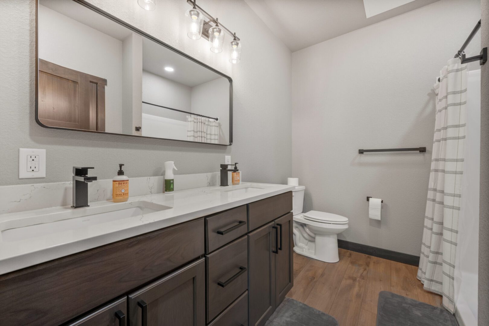 Modern bathroom with dark wood vanity and large mirror.