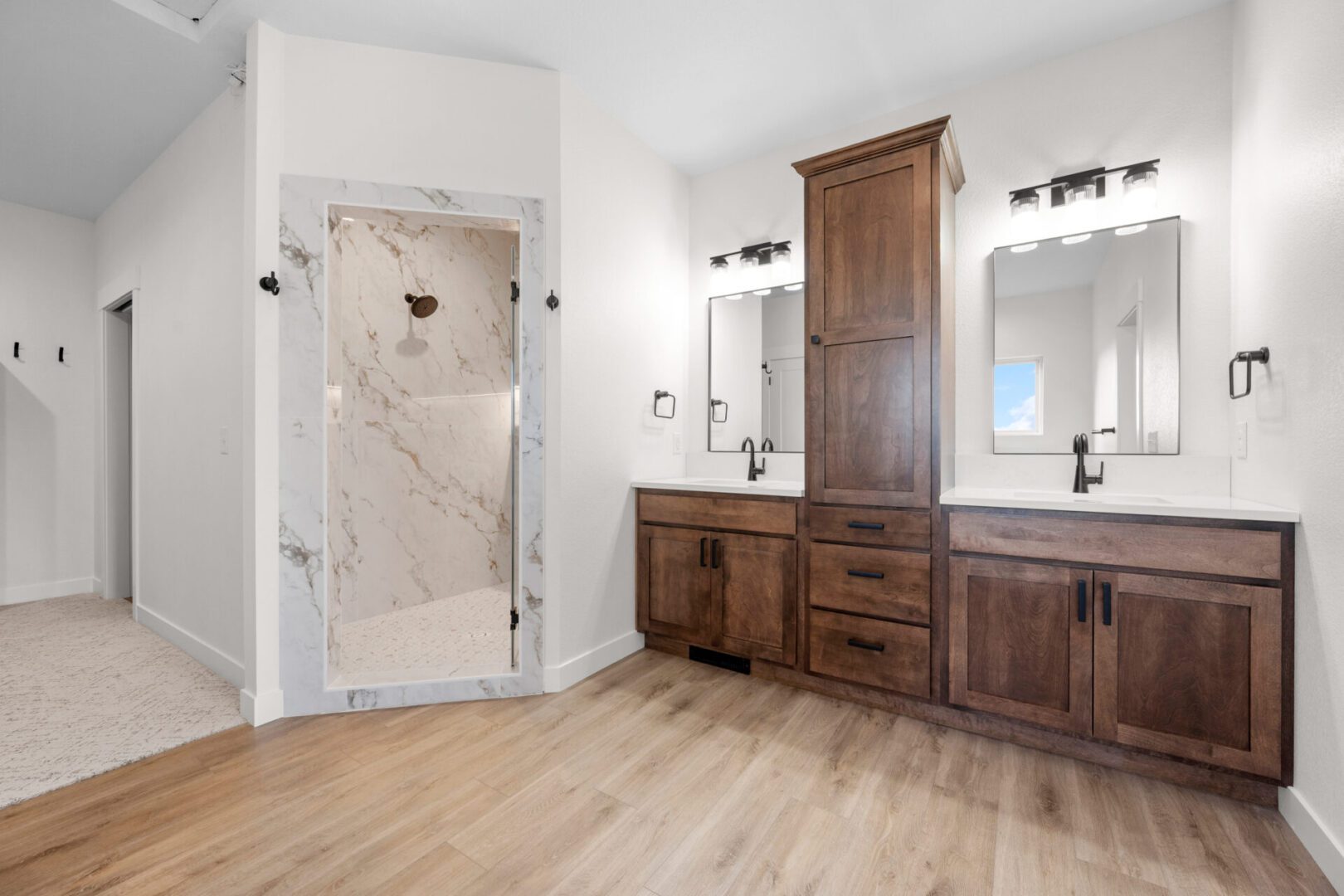 Spacious bathroom with wooden cabinetry and glass-enclosed shower.