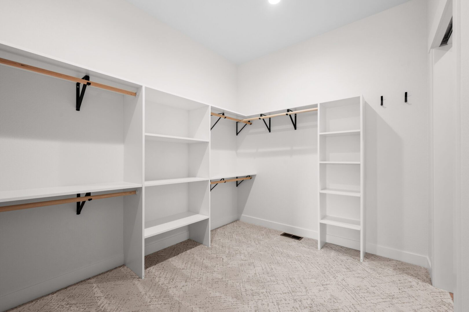 Empty walk-in closet with white shelves and beige carpet.