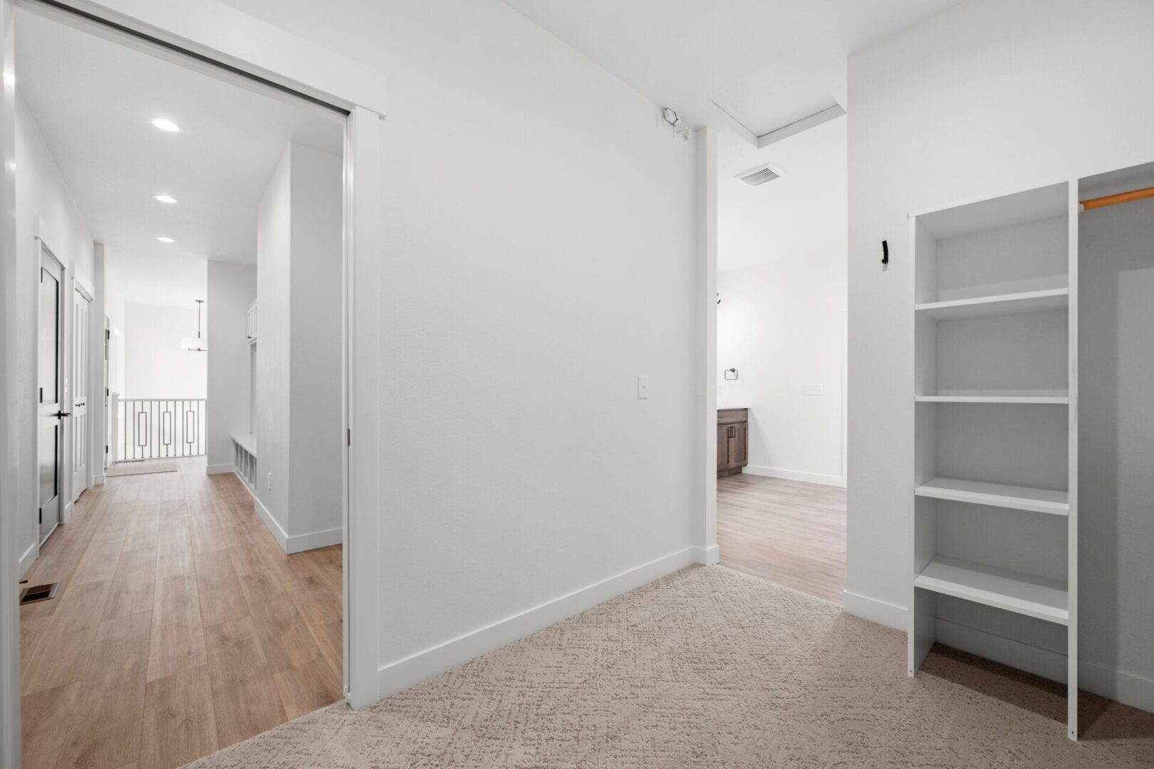 Bright hallway with carpeted floor leading to a bathroom.